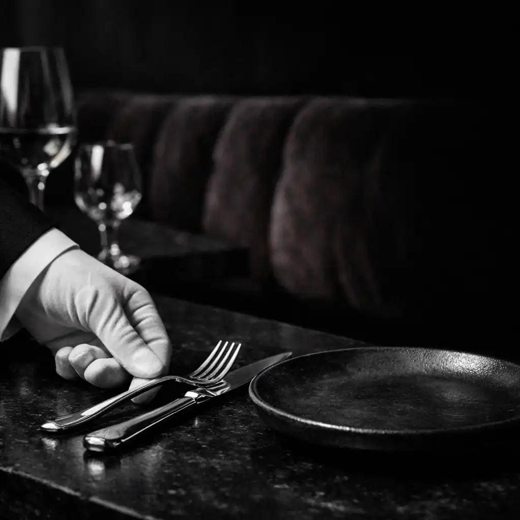 Late-night service placing a finished plate on a dark restaurant table